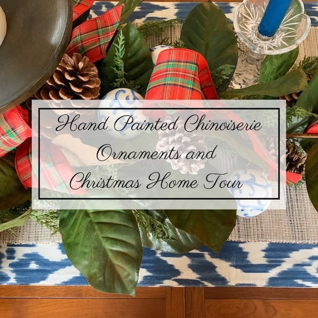 Festive table setting with greenery, pine cones, and red plaid ribbon. Text overlay reads, "Easy Chinoiserie Ornament DIY and Christmas Home Tour." A blue and white patterned runner is partially visible underneath.