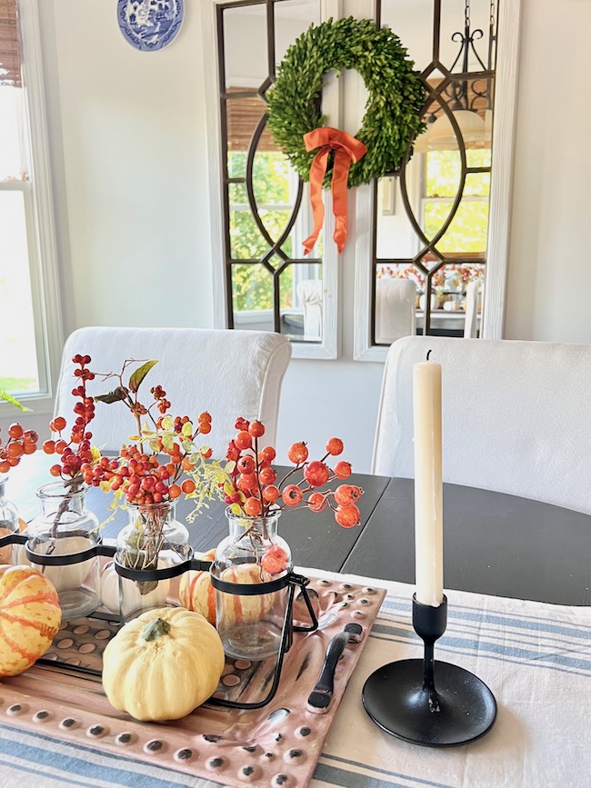 Fall decorating in the kitchen with blue striped table runner and orange berry and pumpkin centerpiece