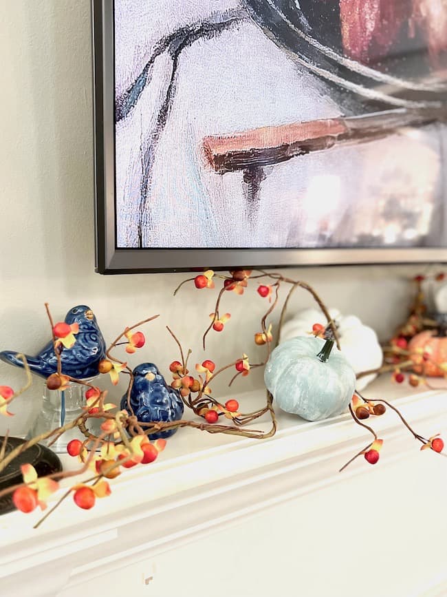 Blue ceramic birds with blue and white mini pumpkins and Orange Bittersweet on fireplace mantel for fall