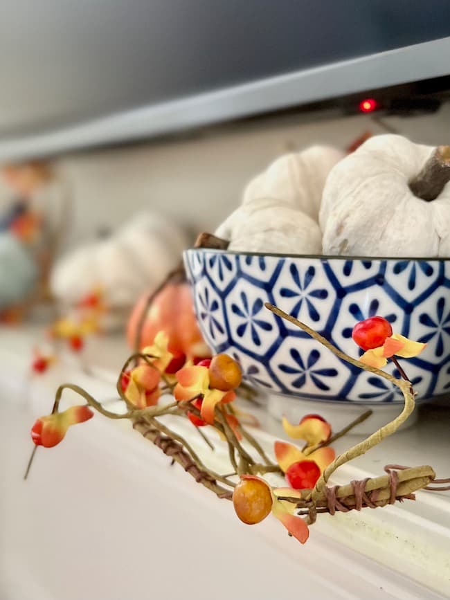 Blue and White Bowl and Orange Bittersweet on fireplace mantel for fall