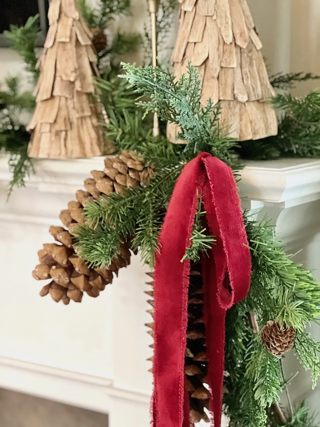 Red velvet ribbon and large pinecones on mantel