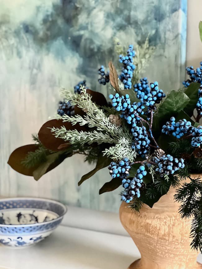 Winter arrangement with blue berry stems and magnolia branches