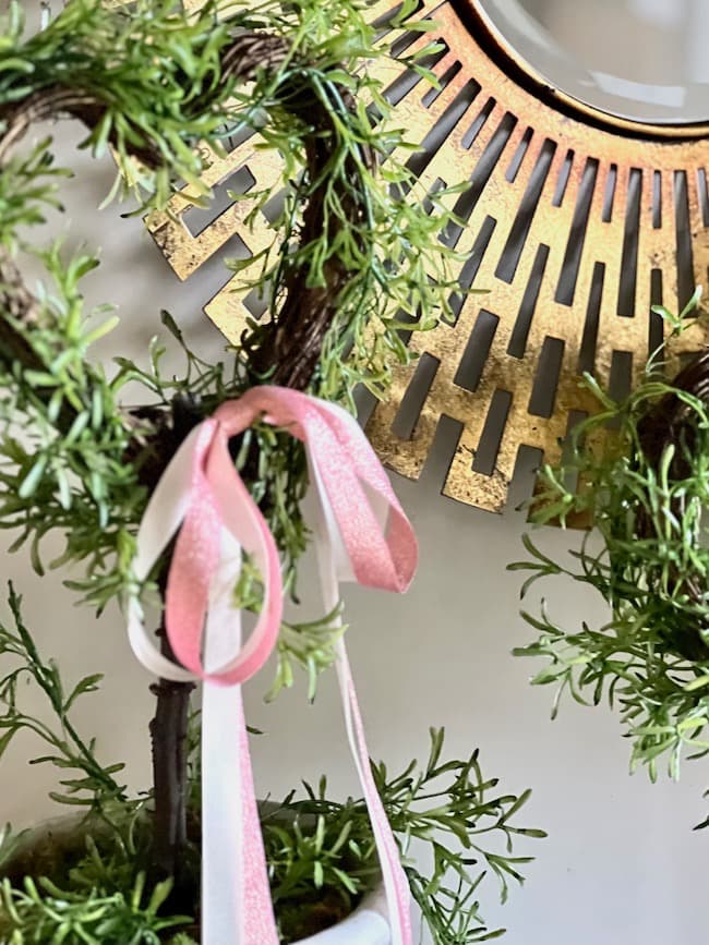 A pink bow is added to a Valentine topiary.