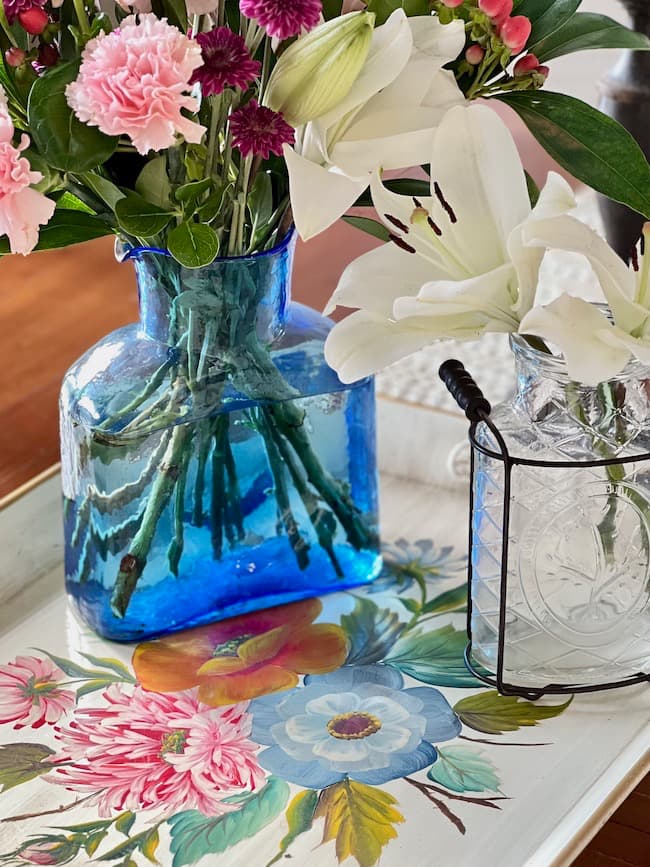 Tole painted tray with blue glass vase and white lilies for table centerpiece