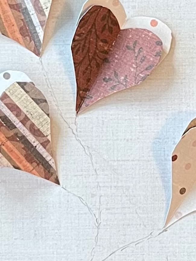 Arrange the hearts on the paper and sketch the stems with a pencil before stitching.
