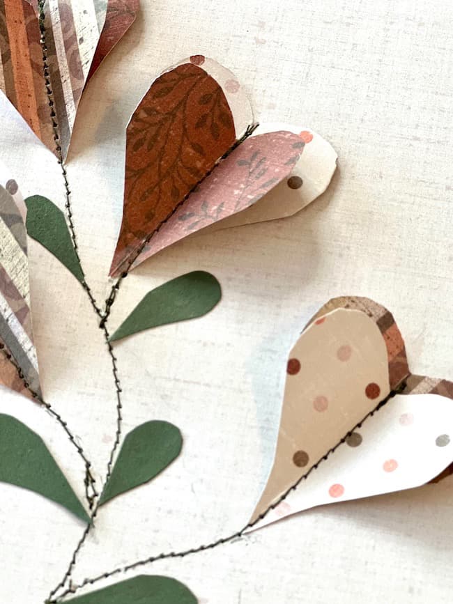 These heart-shaped flowers are created with layers of patterned scrapbook paper and stitched onto a paper backing to create the design.