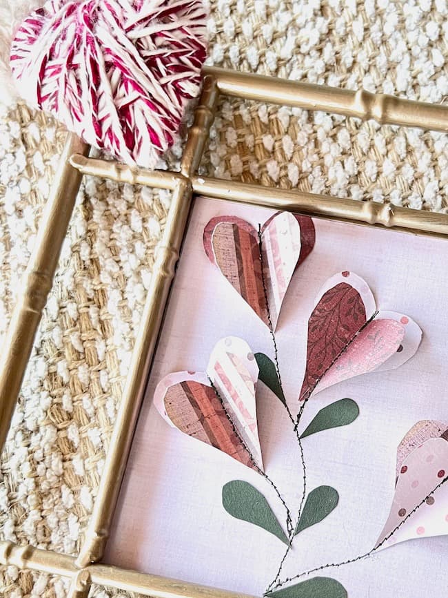 This framed 3D paper artwork features hearts cut from scrapbook paper and stitched onto a backing.