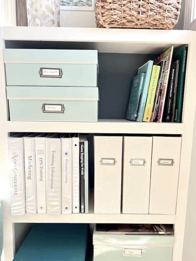 Organize office supplies and materials in boxes and vertical file holder.