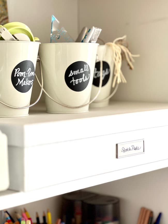 Containers and labeled cups for organizing craft supplies