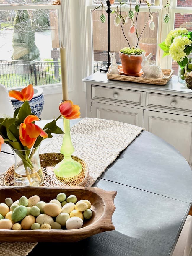 Green and orange Easter decor color scheme with tulip centerpiece on table and kitchen buffet.