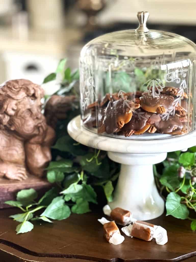 Homemade salted caramel chocolate turtles in a glass pedestal cake stand.