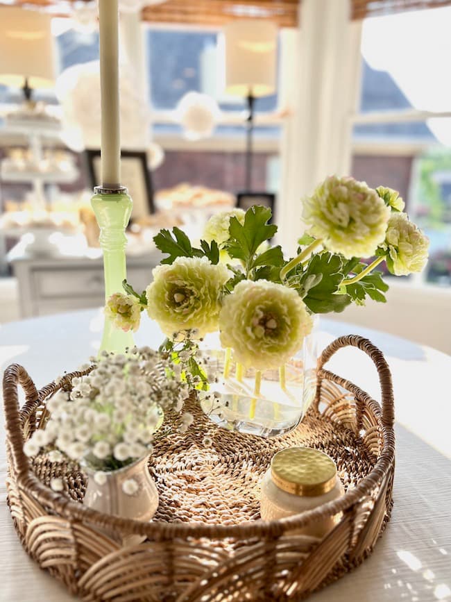 Engagement party centerpiece idea with faux ranunculus and baby's breath arranged in basket tray.