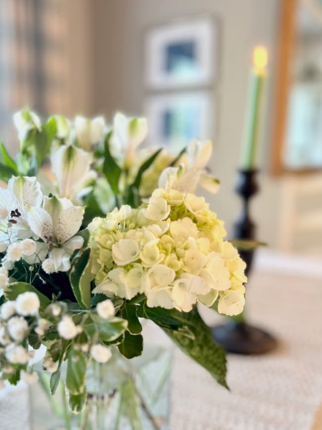 Dining table engagement party centerpiece with white hydrangeas, white alstroemeria, and baby's breath.