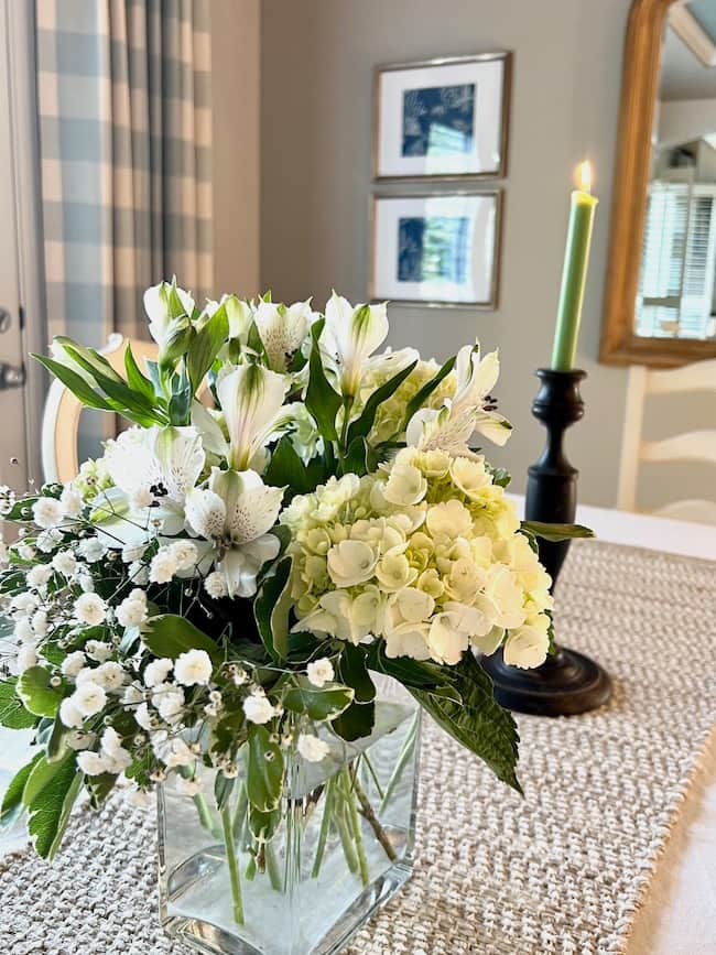 Dining table engagement party centerpiece with white hydrangeas, white alstroemeria, and baby's breath.