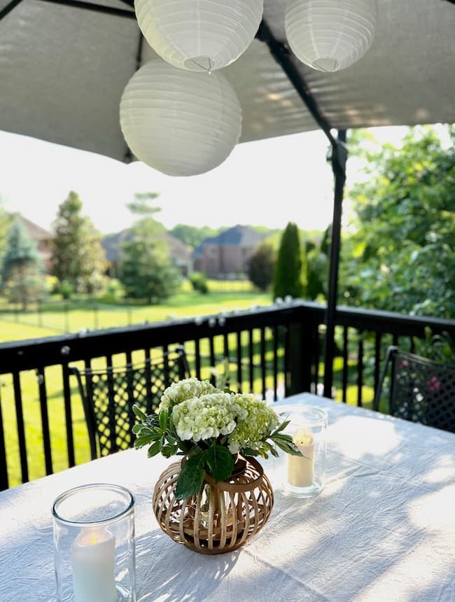 Patio table decor for backyard engagement party with white paper lanterns under umbrella