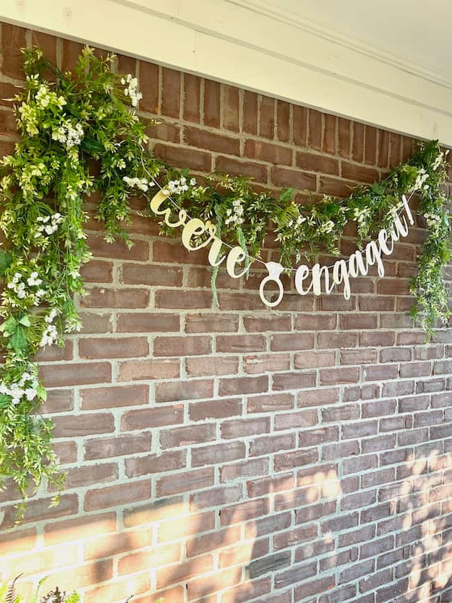 We're Engaged photo backdrop along outdoor brick wall