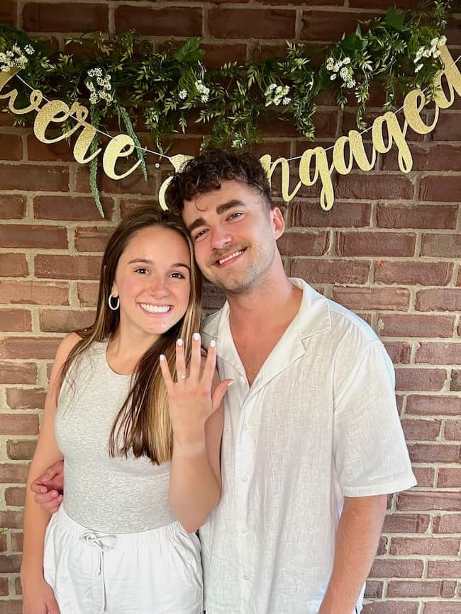 The Happy Couple -- We're Engaged photo backdrop along outdoor brick wall