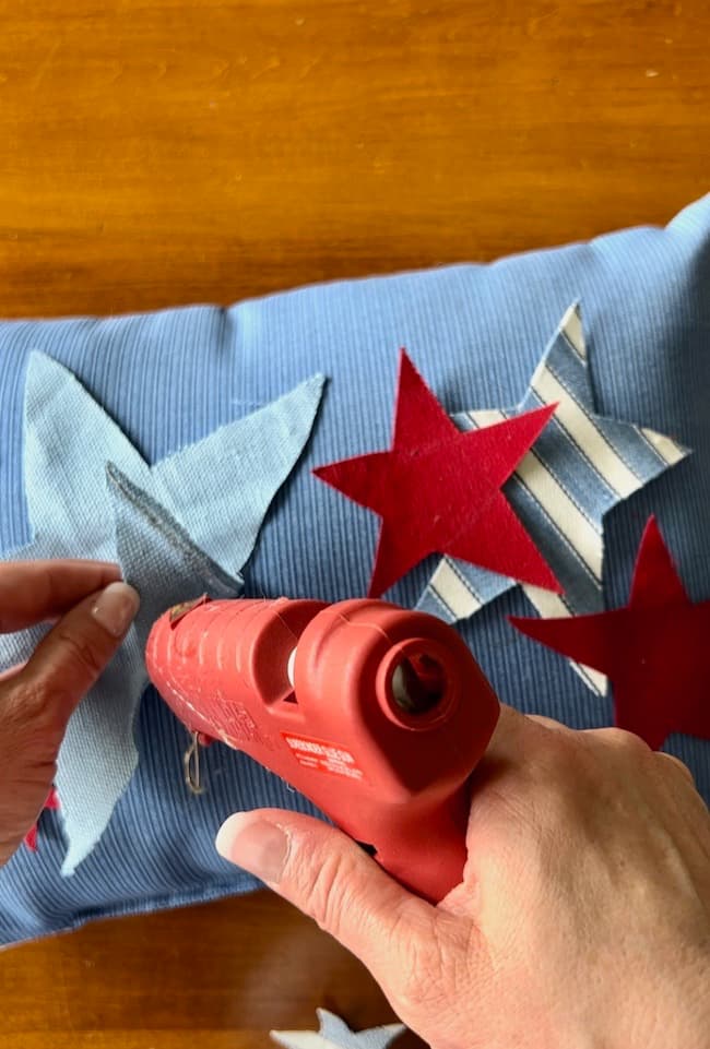 Glue fabric stars onto a DIY Patriotic Star Pillow
