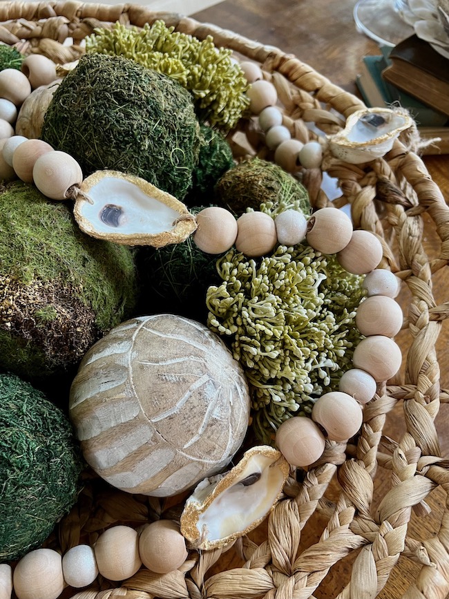 DIY oyster shell garland with wood beads in a woven bowl.