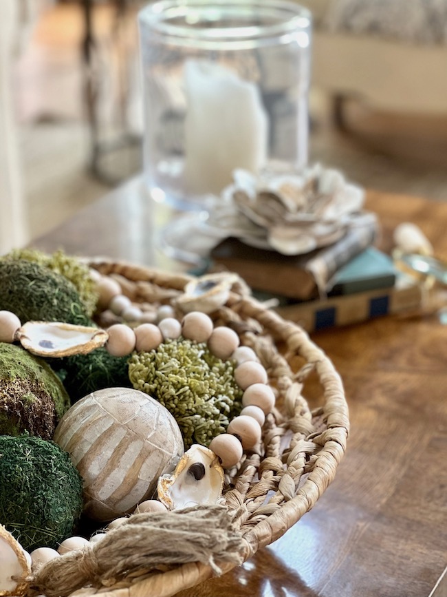 Coffee table style with oyster shell garland and moss balls in a large round textured basket