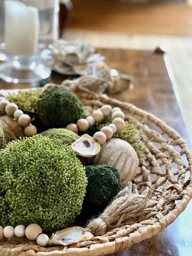 Coffee table style with oyster shell garland and moss balls in a large round textured basket