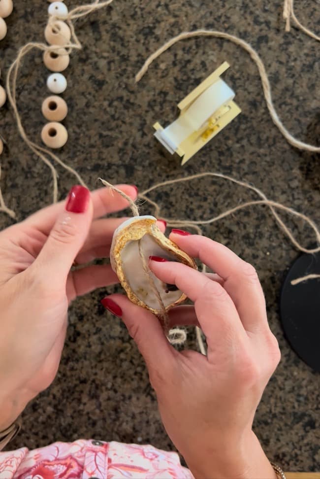 Insert the jute twine through the top hole in the oyster shell.