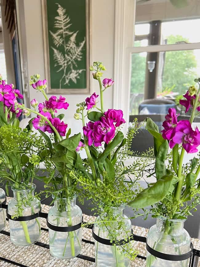 Purple stock in kitchen table arrangement with multi bud vase holder