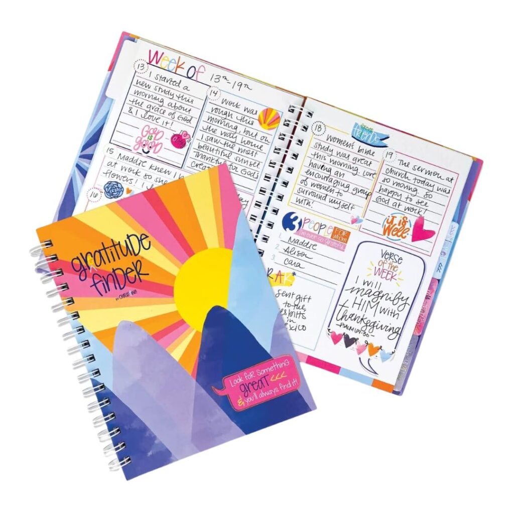 Two colorful Gratitude Finder journals are open, showing off handwritten entries filled with doodles and stickers. One cover depicts a vibrant rainbow sunset over mountains with the text "Gratitude Finder." The interior pages, designed for daily gratitude notes, also provide tips for getting organized.