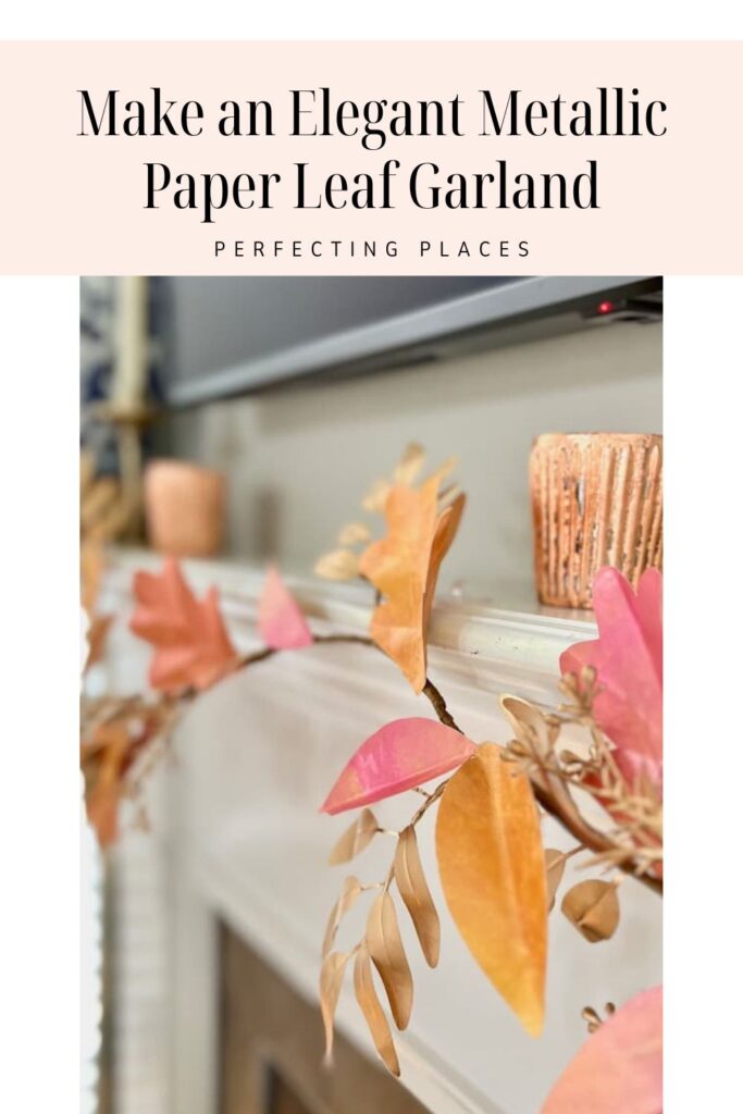 A close-up of a metallic paper leaf garland displayed on a mantle. The garland features different shapes and colors, including gold, orange, and pink leaves—ideal for any DIY paper leaf garland for fall projects. In the background, a wooden candle holder is placed on the mantle. Text at the top reads "Make an Elegant Metallic Paper Leaf Garland - Perfecting Places.