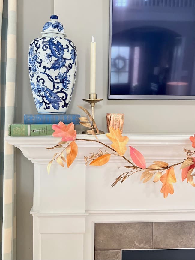 DIY fall garland hanging on the mantel with blue and white vase
