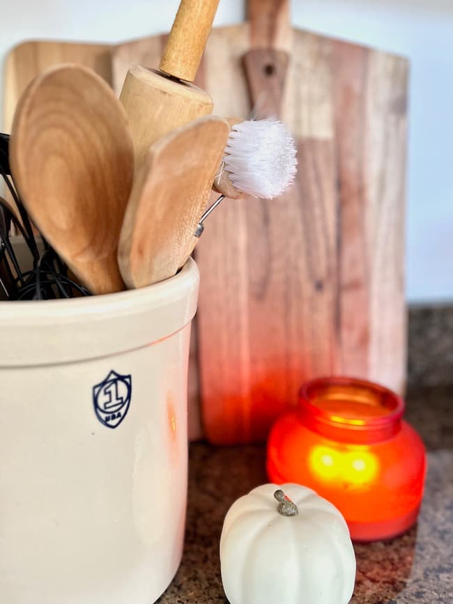 Warm wooden accents with cutting boards and wooden utensils in vintage crock.