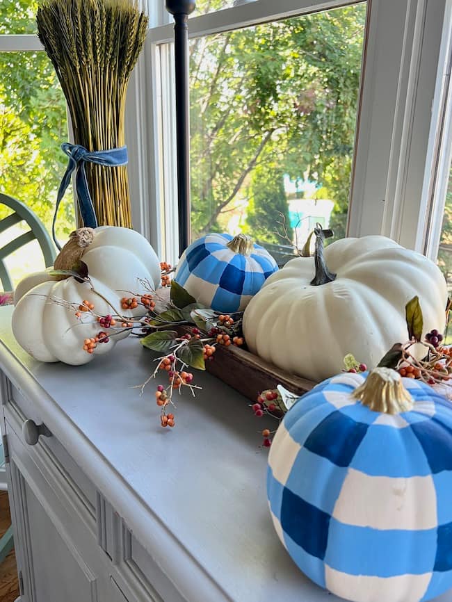 Kitchen Buffet Decorated for Fall with a Dough Bowl full of white pumpkins and blue and white plaid painted pumpkins