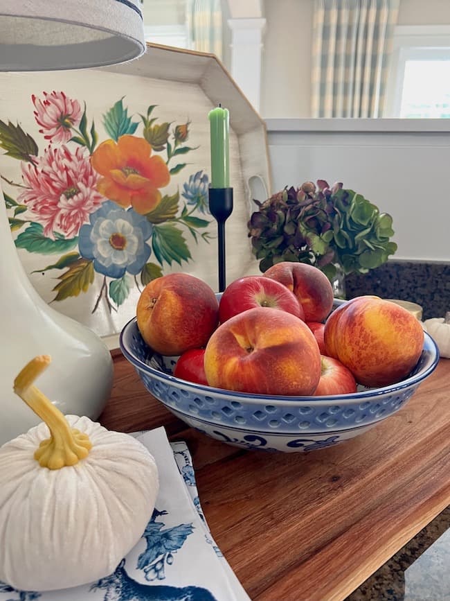 Fall Decor in Kitchen with Tole painted tray, blue and white bowl of apples and peaches, Dried hydrangeas, and white velvet pumpkin