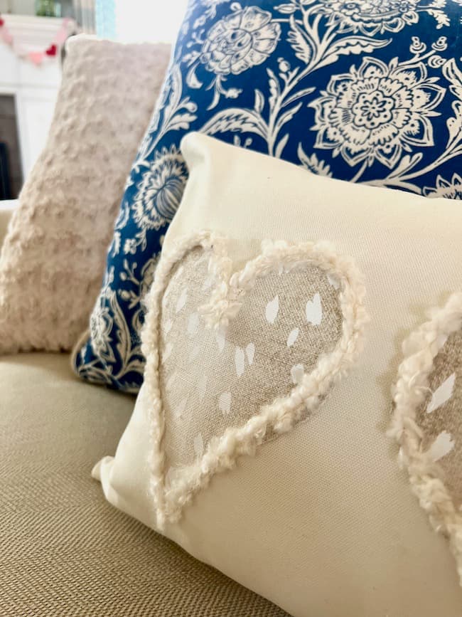 Neutral DIY Valentine pillow on sofa with blue a white throw pillow
