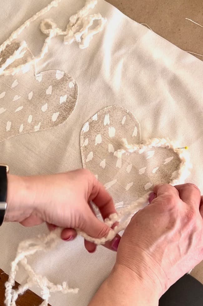 Add fuzzy yarn trim to each fabric heart.