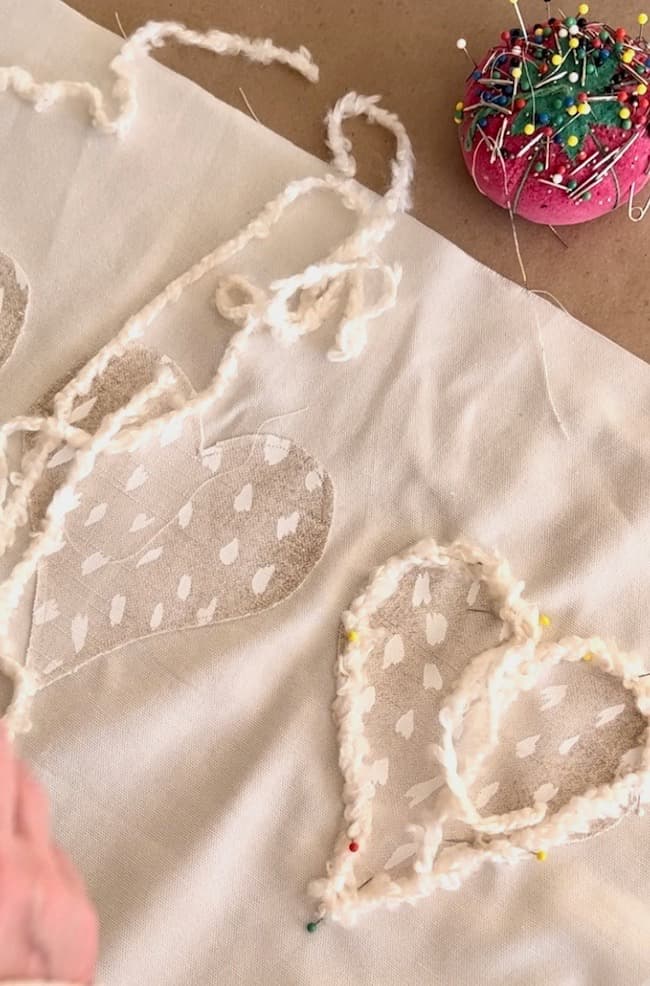 Add fuzzy yarn trim to each fabric heart on the DIY Valentine pillow