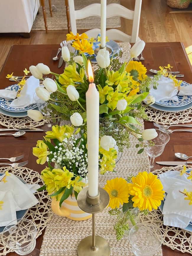 Yellow Gerber daisies, yellow alstroemeria, and white tulips in centerpiece for spring table