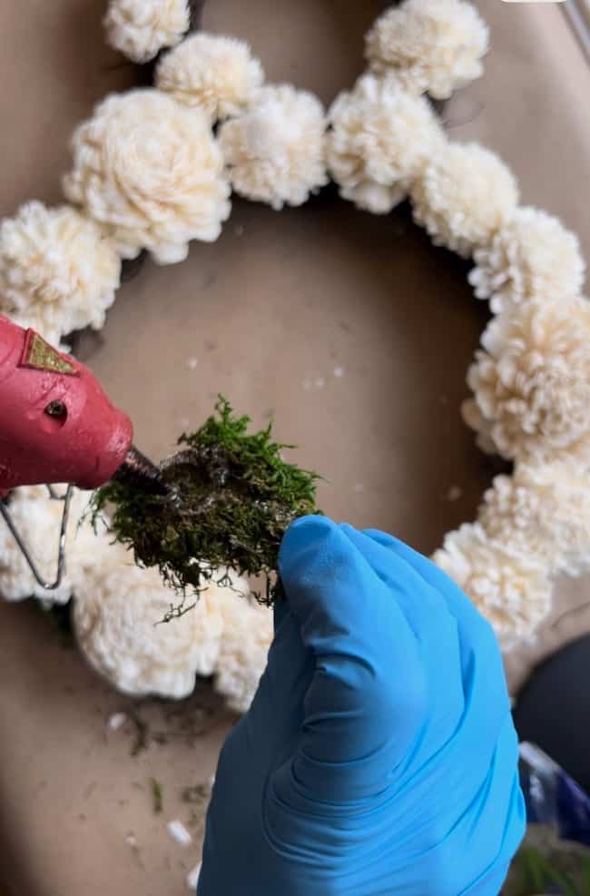 Use a hot glue gun to add moss to a bunny grapevine wreath