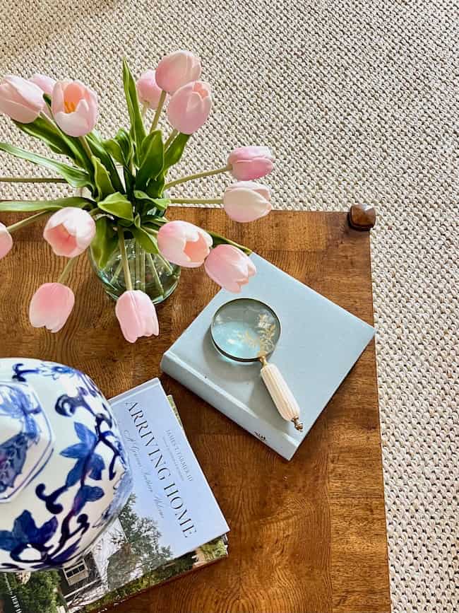 Sisal rug with cream sofa and pink tulips on coffee table with blue and white ginger jar in living room