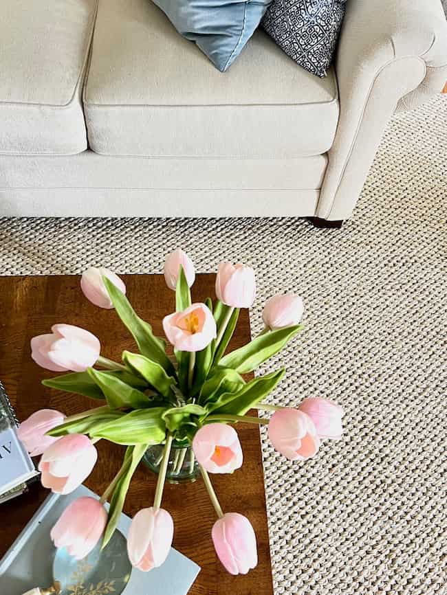 Sisal rug with cream sofa and pink tulips on coffee table in living room