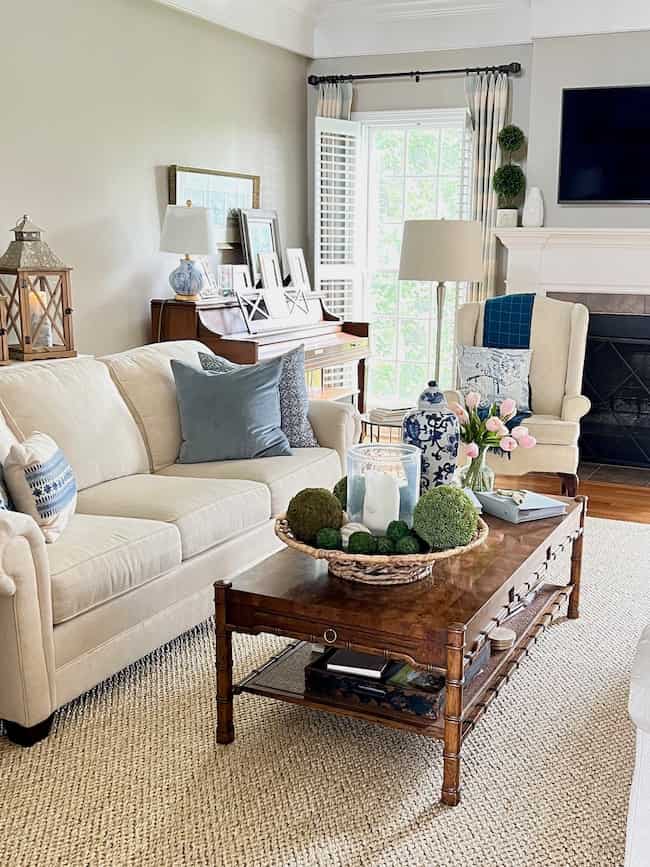 Living room with new Columbia sisal rug from Ballard Designs. Cream sofa with blue patterned accent pillows and Hollywood regency vintage coffee table.
