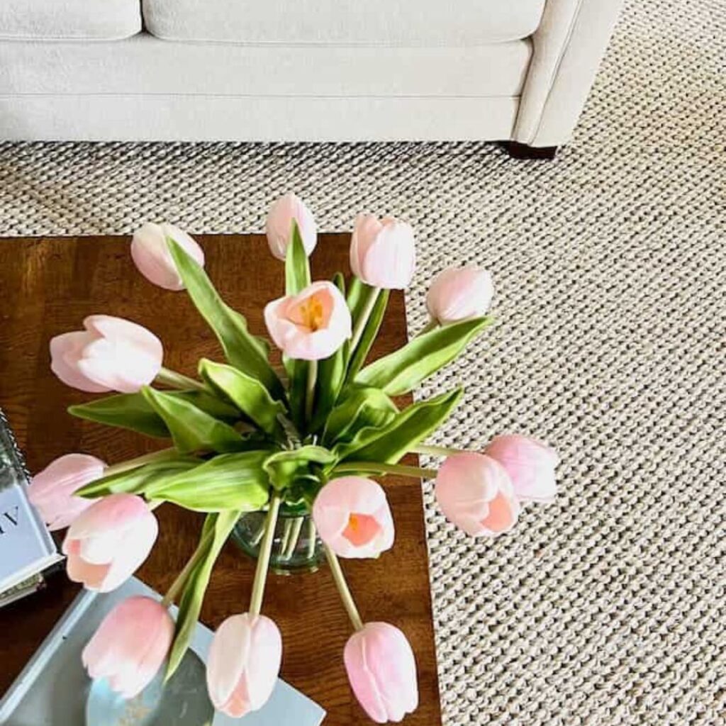 Sisal rug with cream sofa and pink tulips on coffee table in living room -- Jute vs. sisal rug