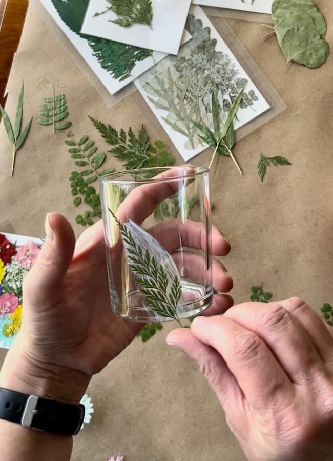 Attaching the pressed fern stem to the glass votive holder with glue.