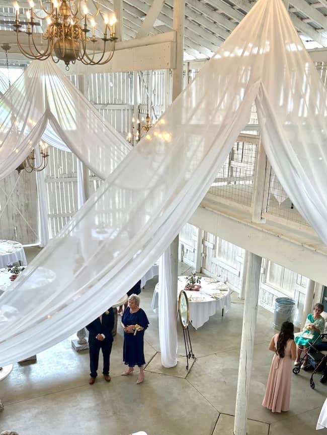 Wedding venue in large white barn with white draping and chandeliers