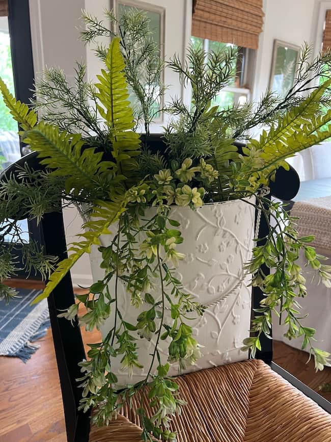 Begin by adding the faux greenery to the white flower bucket.