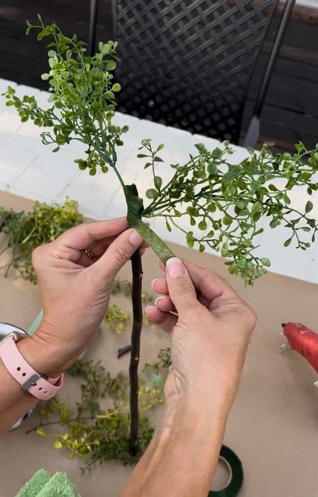 Attach the greenery to the top of the stem with floral tape