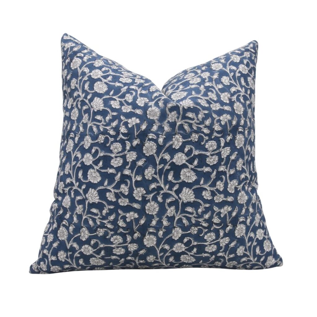 A budget-friendly square pillow with a navy blue background featuring an intricate white floral pattern. The pillow has a smooth texture and is plump, giving it a full, plush appearance. The detailed floral design covers the entire front of this elegant piece.