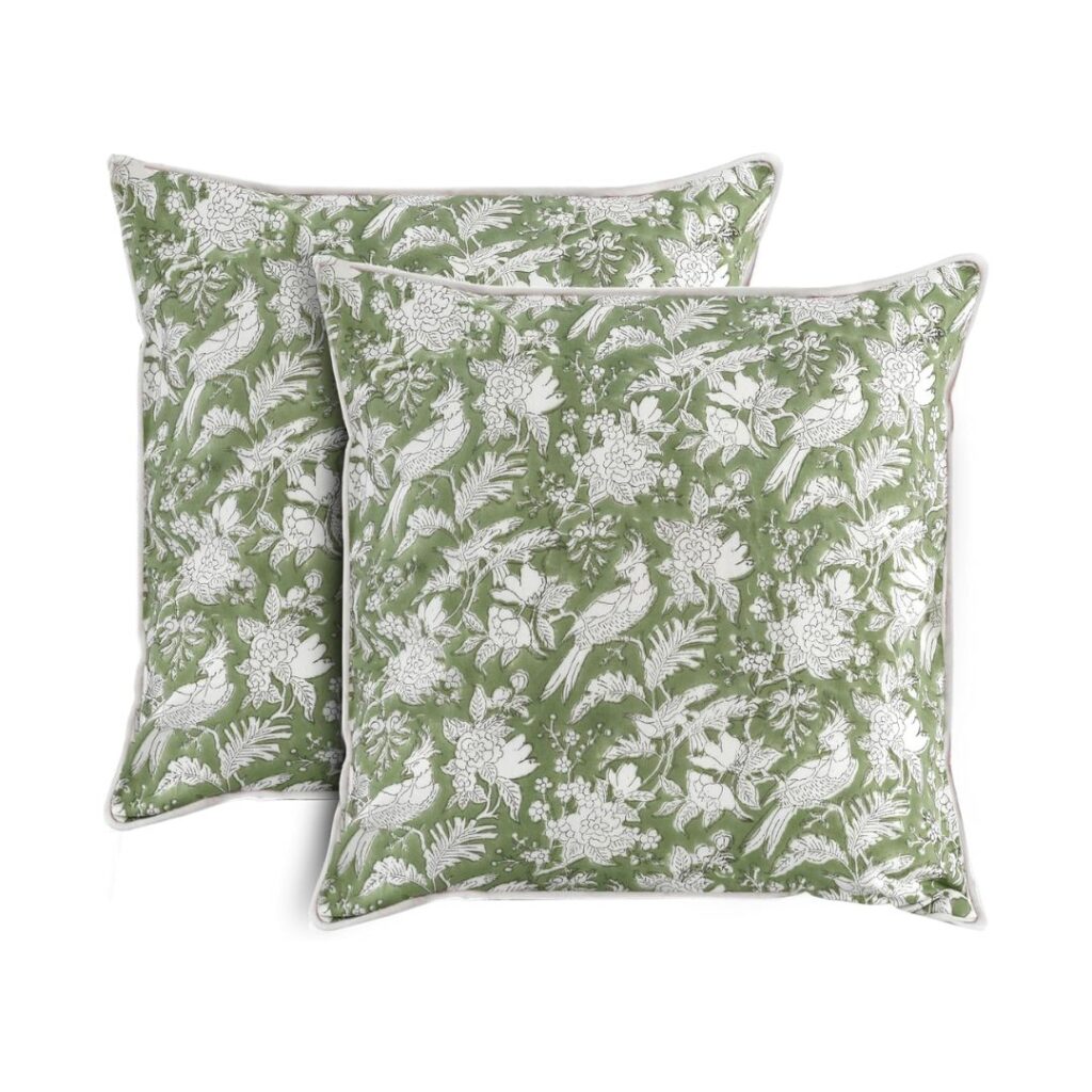 Two decorative, budget-friendly pillows with a green background and white botanical patterns, including birds, flowers, and leaves. The cushions are placed overlapping each other, showcasing their detailed and intricate design. Available on Amazon for your convenience.