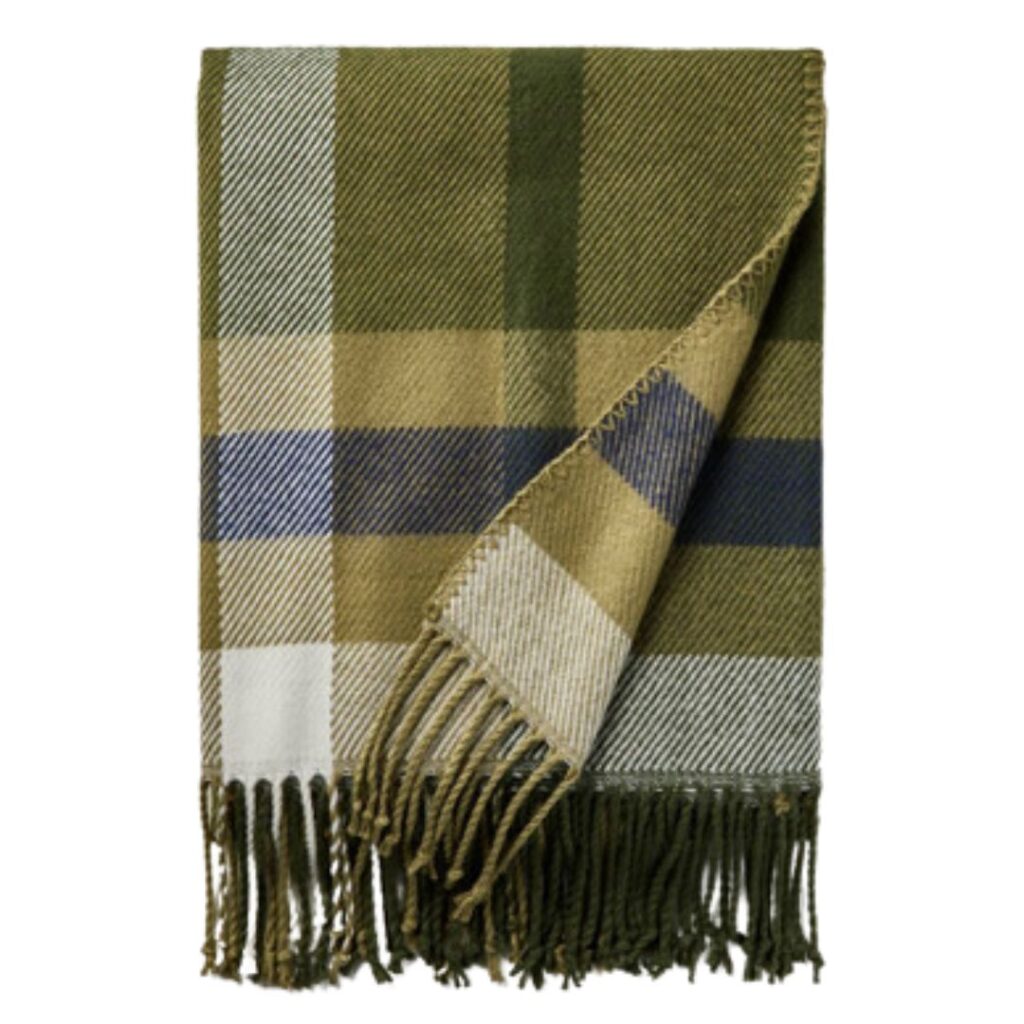 A folded, rectangular blanket with a plaid pattern featuring shades of green, beige, white, and blue. One corner is flipped over, showing the reverse side, and fringes are visible along the bottom edge. Perfect for affordable Target home decor and ideal for fall decorating trends.