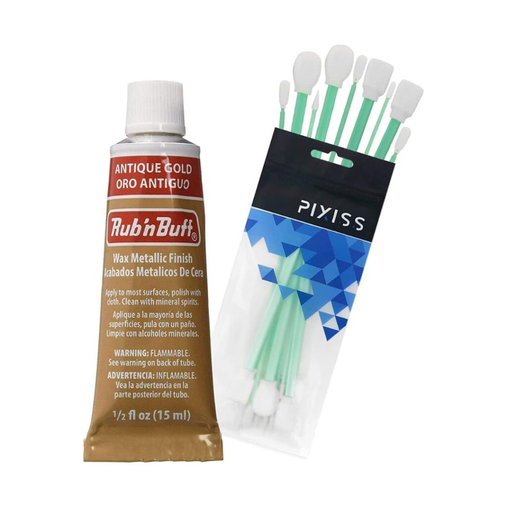 A 15 ml tube of Rub 'n Buff Wax Metallic Finish in Antique Gold, perfect for enhancing a picture frame, sits beside a pack of Pixiss foam-tipped applicator swabs. The tube features a brown label with white text and a white cap, while the pack has a black and blue label with several green-handled swabs.